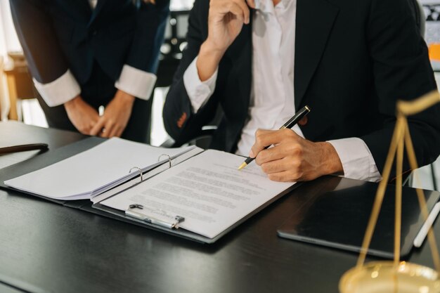 事務所の机の上に真鍮のスケールで契約書を議論するビジネスと弁護士 法務サービスは、オフィスで正義と法律の概念をアドバイスします