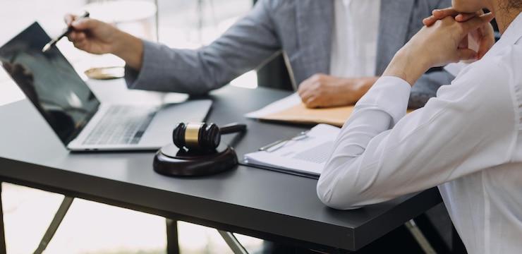 Business and lawyers discussing contract papers with brass scale on desk in office Law legal services advice justice and law concept picture with film grain effect