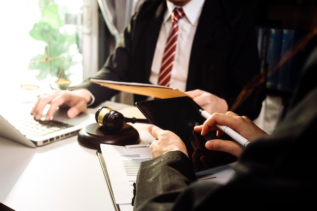 Photo business and lawyers discussing contract papers with brass scale on desk in office law legal services advice justice and law concept picture with film grain effect