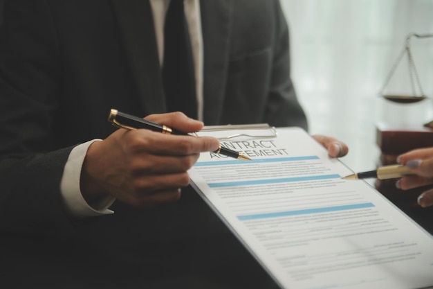 Business and lawyers discussing contract papers with brass scale on desk in office Law legal services advice justice and law concept picture with film grain effect