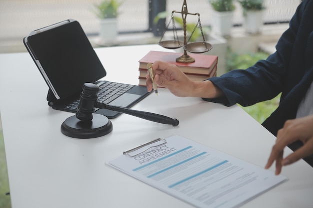 Business and lawyers discussing contract papers with brass scale on desk in office law legal services advice justice and law concept picture with film grain effect