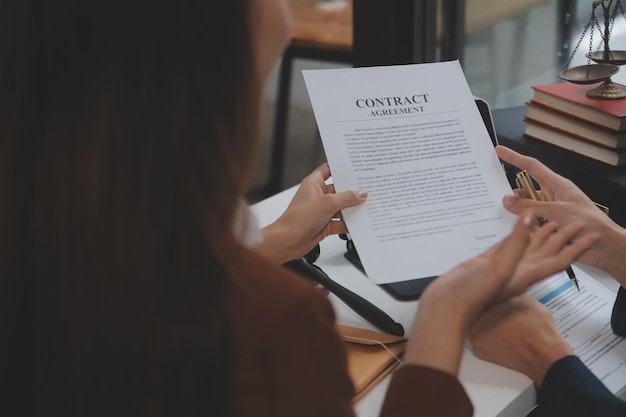 Business and lawyers discussing contract papers with brass scale on desk in office Law legal services advice justice and law concept picture with film grain effect