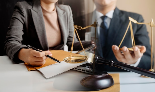 Business and lawyers discussing contract papers with brass scale on desk in office Law legal services advice justice and law concept picture with film grain effect