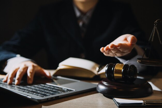 オフィスの机の上で真ちゅう製の目盛り付きの契約書について話し合うビジネスと弁護士法律法務サービスアドバイス正義と法の概念