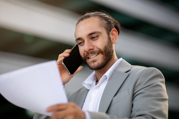 Business lifestyle confident young businessman talking on cellphone and looking at documents