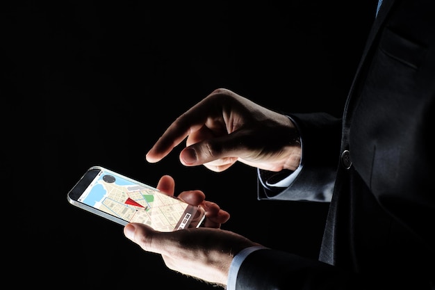 business, locatie, mensen en toekomstig technologieconcept - close-up van zakenmanhanden met transparante smartphone met gps-navigatorkaart op het scherm op zwarte achtergrond