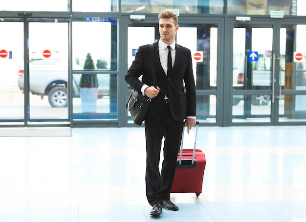 Business man at airport with suitcase - travel concept