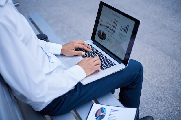 Business man analyzing financial data while sitting on a bench