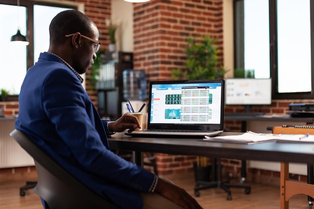 Business man analyzing stock market data chart for company growth on laptop. Entrepreneur looking at global money trade to invest in crypto currency and work on startup project.