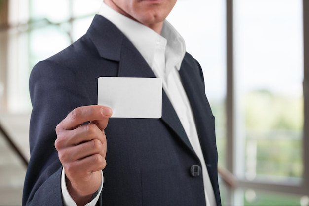 Business man in black suit holding white card on background