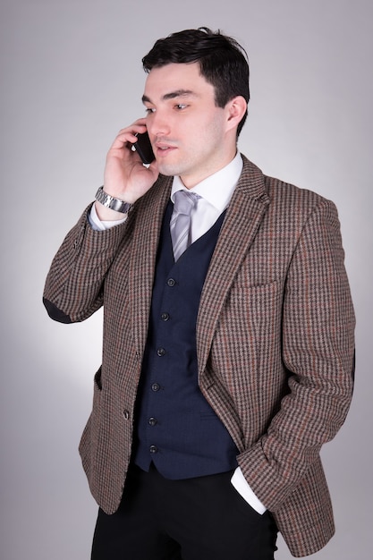 Business man calling on mobile phone over grey background