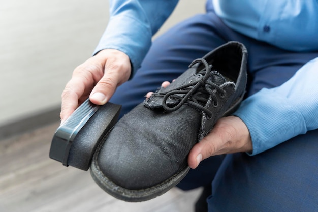 Business man cleans his black shoes with a sponge. hand\
polishing black men\'s boot