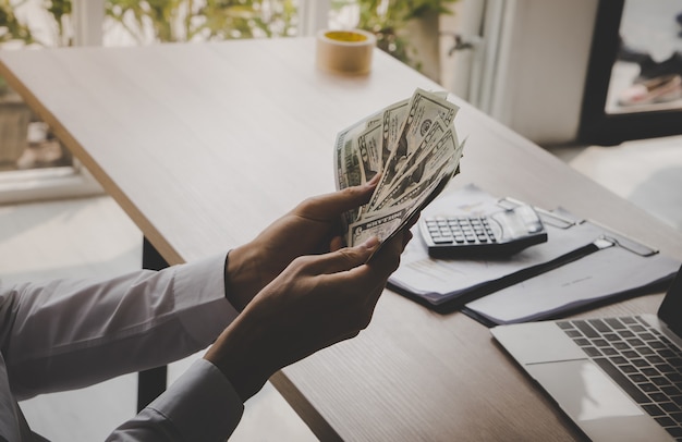 Бизнесмен подсчитывая деньги долларовой банкноты в офисе