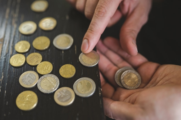 돈을 세는 사업가. 부유한 남성의 손은 테이블에 다른 유로의 동전을 들고 계산합니다.