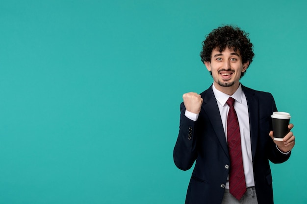 Uomo d'affari riccio carino bel ragazzo in abito nero e cravatta rossa che tiene eccitantemente un pugno in su