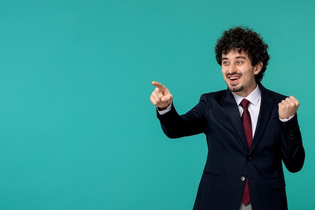 Business man curly cute handsome guy in black suit and red tie holding fist up and smiling