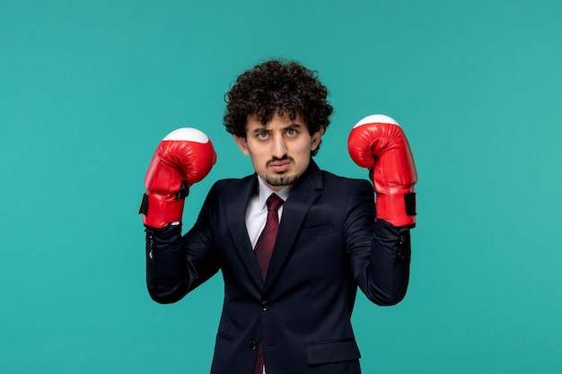 Business man curly cute handsome guy in black suit and red tie ready to fight in boxing gloves