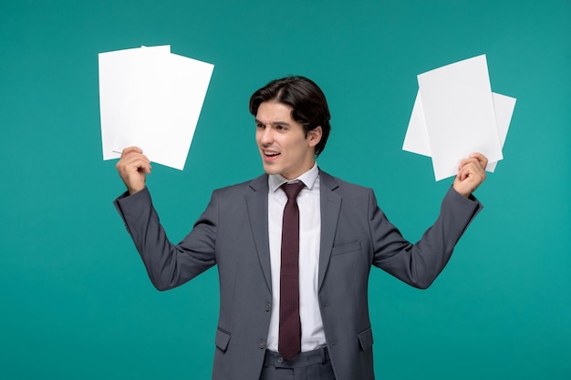 Business man cute handsome guy in grey office suit and tie raising hands with paper sheets