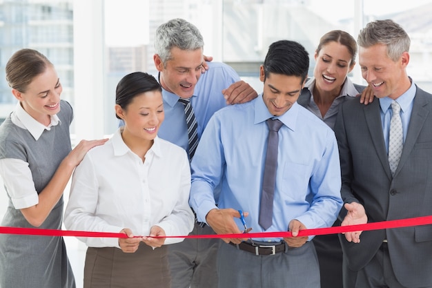 Business man cutting red strip 