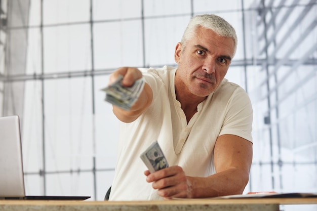 Business Man Displaying a Spread of Cash over a office background