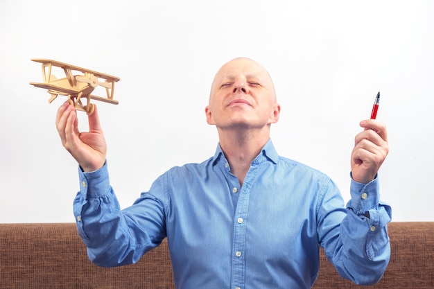 Business man dreams of his achievement Business dream concept A man holds a wooden airplane model in his hands