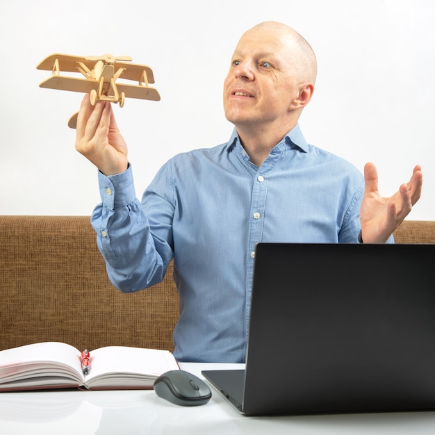 Business man dreams of his achievement Business dream concept A man holds a wooden airplane model in his hands