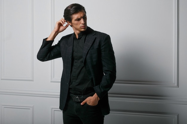 Business man dressed in black suit portrait against a white background. Portrait handsome young man, looking at the side.