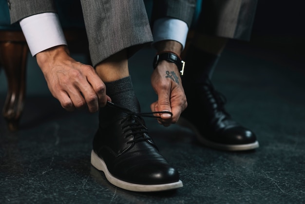 Uomo d'affari vestirsi con scarpe classiche ed eleganti che legano lacci delle scarpe