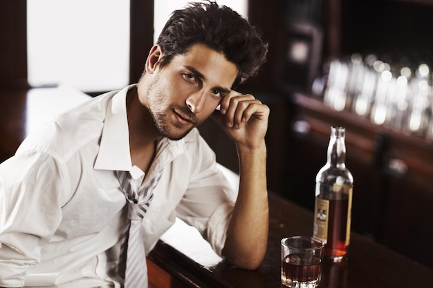 Business man drinking and portrait in happy hour at a bar with alcohol and whiskey after work Bottle male person and face in a restaurant with a playboy guy and a glass and confidence in pub