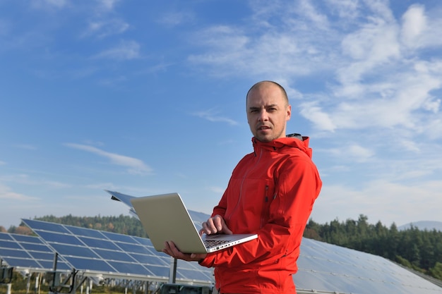 business man  engineer using laptop at solar panels plant eco energy field  in background