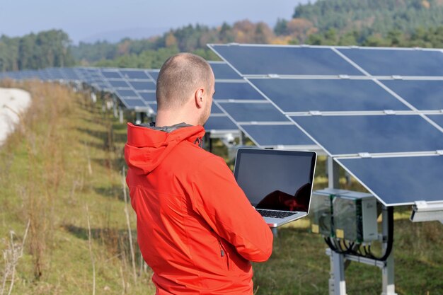 Business man engineer using laptop at solar panels plant eco energy field in background