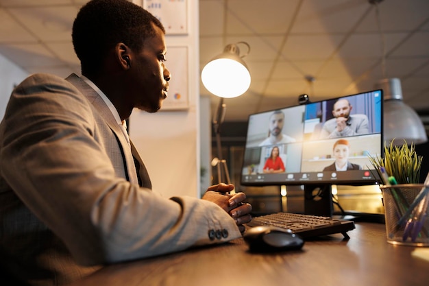 Business man explaining financial statistics report, discussing company strategy with remote team during online videocall meeting conferece. Corporate employees working overhours in startup office