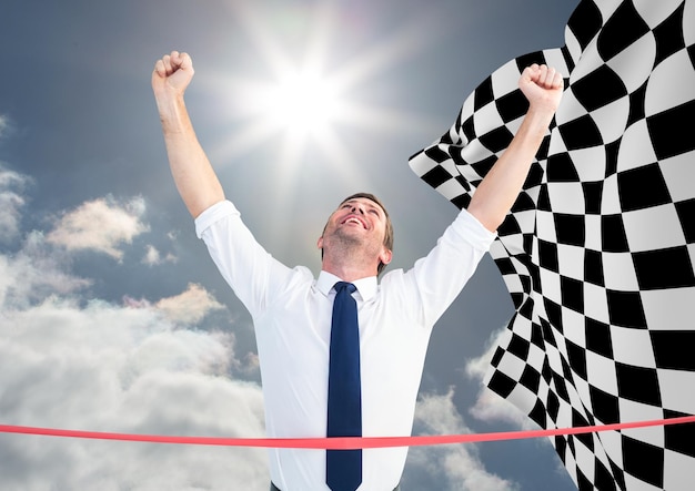 Business man at finish line against sky and checkered flag