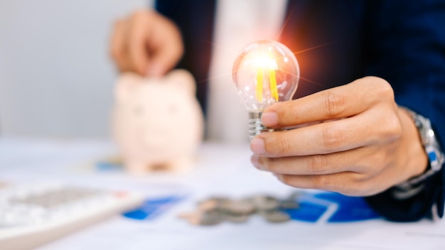 Business man hand holding lightbulb with using calculator to calculate and money stack.