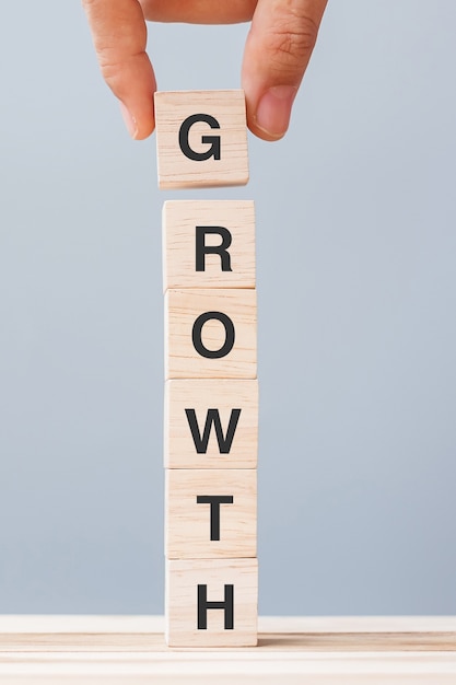 写真 growthビジネスワードで木製の立方体ブロックを持っているビジネスマンの手。成功、利益、経済、金融の概念