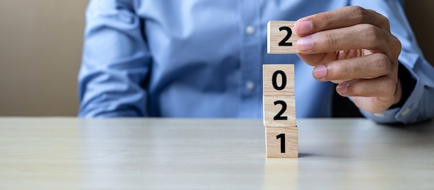 Business man hand holding wooden cube blocks with 2021