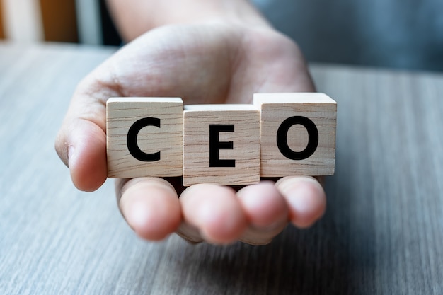 Business man hand holding wooden cube with CEO text 