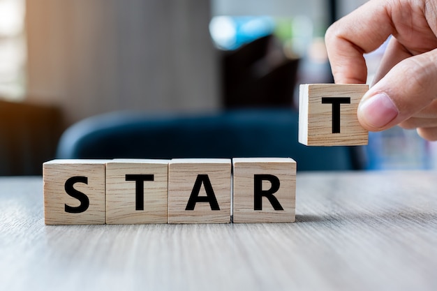 Business man hand holding wooden cube with START text 