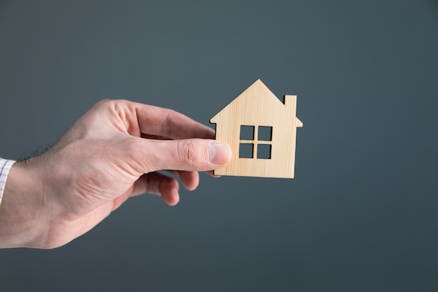 business man hand holding wooden house