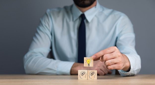 Business man hand light bulb on wooden cubes