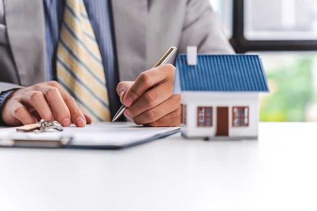 Руки бизнесмена с концепцией страхования недвижимости модели дома Ипотека и уплата налогов