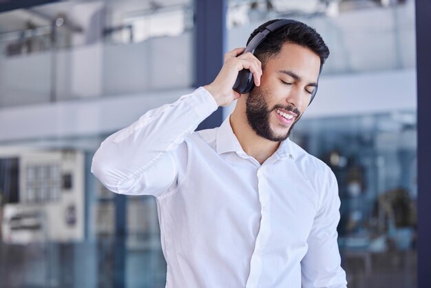 Business man headphones and listening to music in office for motivation inspiration or freedom on break Happy young worker listen to audio radio or podcast for happiness smile and fun in startup