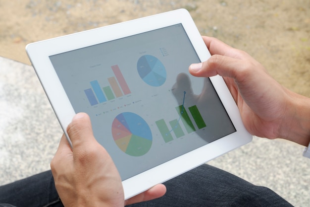 business man hold analyzing financial chart on tablet , strategy concept , business idea , business concept&#xA;&#xA;