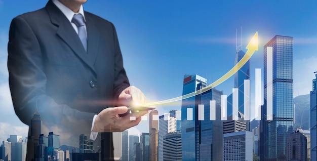 Photo business man hold mobile present chart up of business success plan, financial, profit growth, stock. businessman use smart phone show arrow graph up of building, office tower, property, real estate.