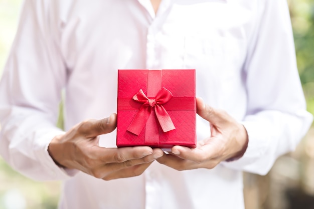 Contenitore di regalo rosso della stretta dell'uomo di affari in mani.