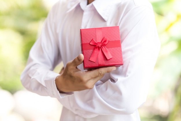 Деловой человек держать красную подарочную коробку в руках.