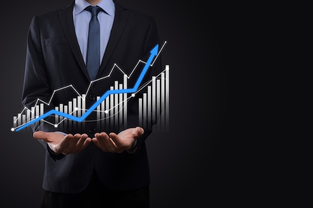 L'uomo di affari che tiene i grafici olografici e le statistiche del mercato azionario guadagna i profitti