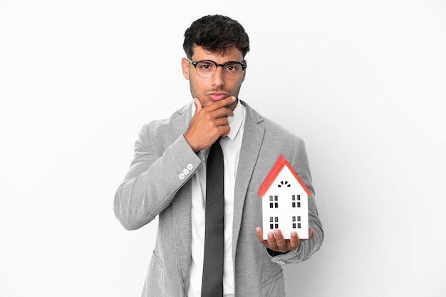 Business man holding a house isolated on blue background thinking