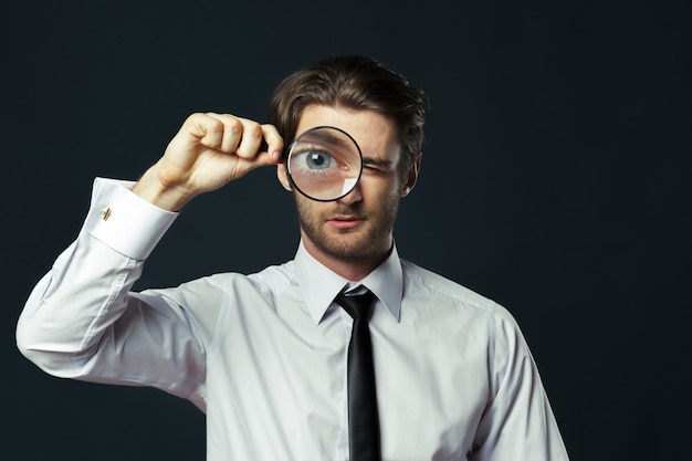 Business man holding magnifying glass 