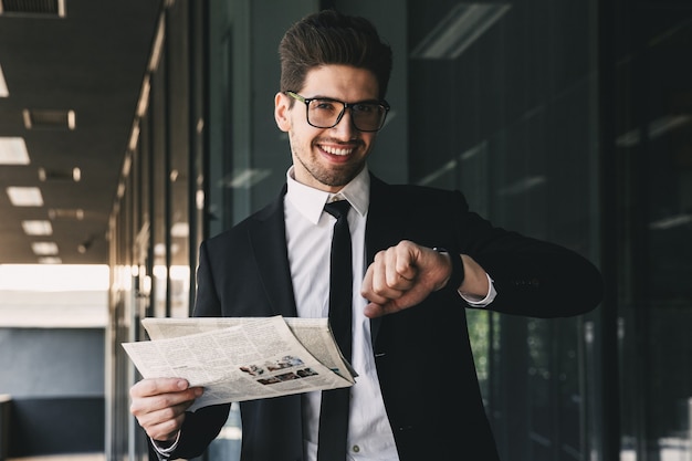 Business man holding newspaper looking at watch clock.